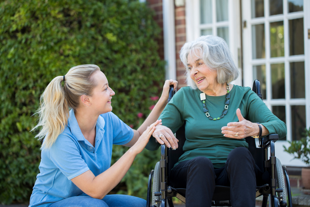 Carer Pushing Senior Woman In Wheelchair