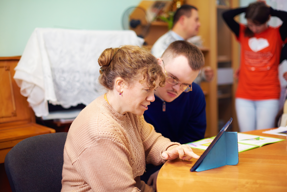 two friends with disabilities watching digital tablet