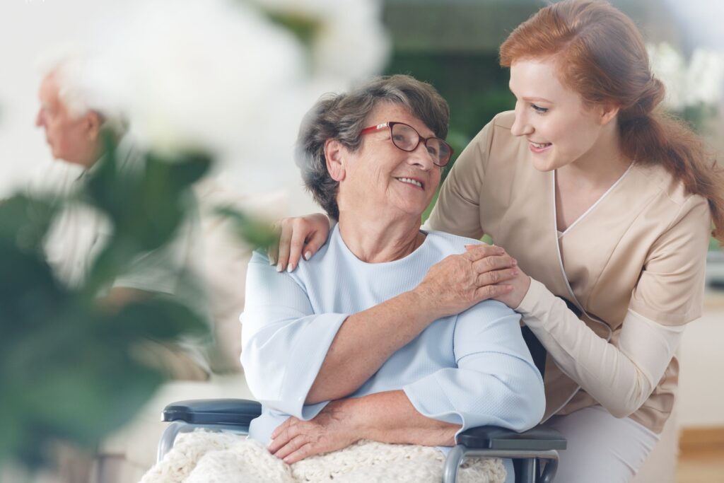care worker smiling and helping elderly lady in wheelchair